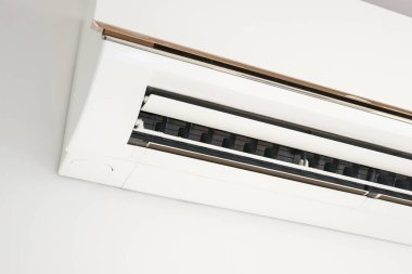 Beyaz duvar odasının arka planında klima var.