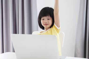 Küçük Asyalı kız öğrenci çevrimiçi evde dizüstü bilgisayar kullanıyor.