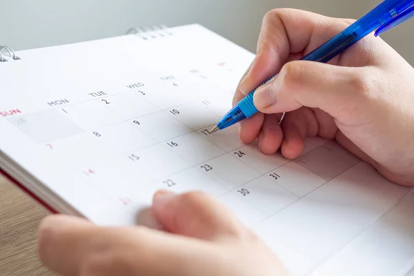 Woman hand with pen writing on calendar date business planning appointment meeting concept