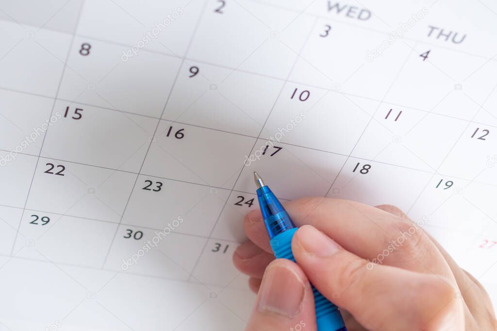 Woman hand with pen writing on calendar date business planning appointment meeting concept