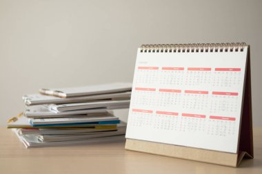 Takvim sayfası beyaz duvar arkası iş görüşmesi konseptiyle ahşap masaya yakın.