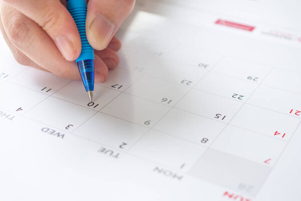 Woman hand with pen writing on calendar date business planning appointment meeting concept