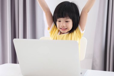 Küçük Asyalı kız öğrenci çevrimiçi evde dizüstü bilgisayar kullanıyor.