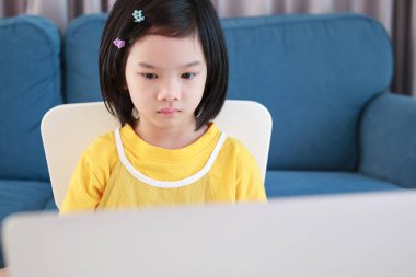 Küçük Asyalı kız öğrenci çevrimiçi evde dizüstü bilgisayar kullanıyor.