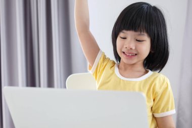 Küçük Asyalı kız öğrenci çevrimiçi evde dizüstü bilgisayar kullanıyor.