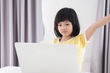 Küçük Asyalı kız öğrenci çevrimiçi evde dizüstü bilgisayar kullanıyor.