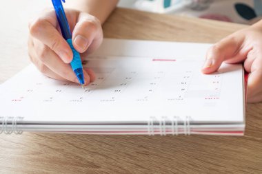 Takvim tarihi iş planlama randevusu konsepti üzerine kalem yazan kadın eli