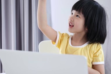 Küçük Asyalı kız öğrenci çevrimiçi evde dizüstü bilgisayar kullanıyor.