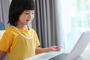 Küçük Asyalı kız öğrenci çevrimiçi evde dizüstü bilgisayar kullanıyor.