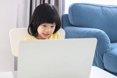 Küçük Asyalı kız öğrenci çevrimiçi evde dizüstü bilgisayar kullanıyor.