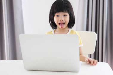 Küçük Asyalı kız öğrenci çevrimiçi evde dizüstü bilgisayar kullanıyor.