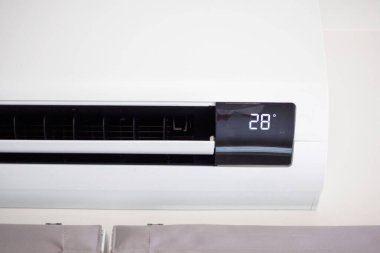 Beyaz duvar odasının arka planında klima var.