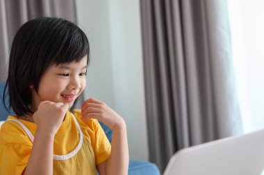 Küçük Asyalı kız öğrenci çevrimiçi evde dizüstü bilgisayar kullanıyor.