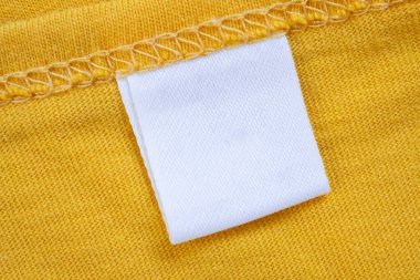 Yeni sarı gömlek arka planında beyaz boş giyim etiketi