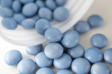 Beyaz arka planda şişesi olan mavi ilaç hapları