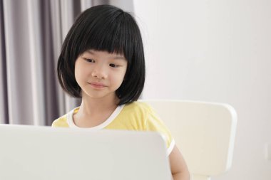 Küçük Asyalı kız öğrenci çevrimiçi evde dizüstü bilgisayar kullanıyor.