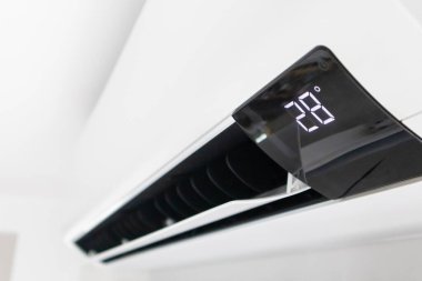 Beyaz duvar odasının arka planında klima var.