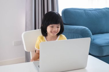 Küçük Asyalı kız öğrenci çevrimiçi evde dizüstü bilgisayar kullanıyor.