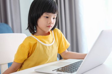 Küçük Asyalı kız öğrenci çevrimiçi evde dizüstü bilgisayar kullanıyor.