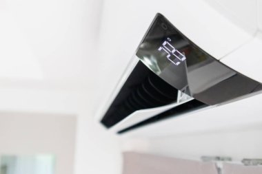 Beyaz duvar odasının arka planında klima var.