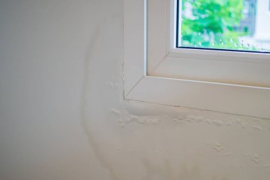 Pencerenin yanındaki duvarda su lekesi var, boya soyuluyor.