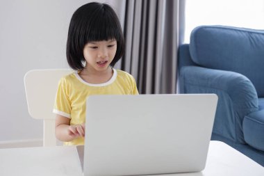 Küçük Asyalı kız öğrenci çevrimiçi evde dizüstü bilgisayar kullanıyor.