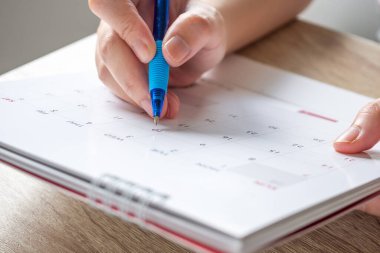 Takvim tarihi iş planlama randevusu konsepti üzerine kalem yazan kadın eli