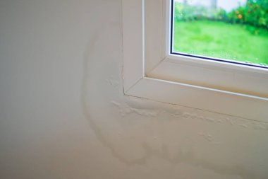 Pencerenin yanındaki duvarda su lekesi var, boya soyuluyor.