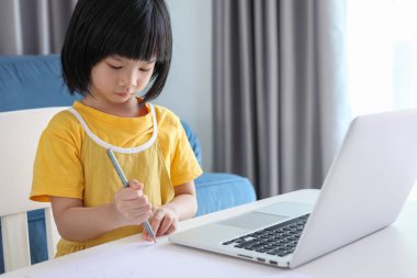 Küçük Asyalı kız öğrenci çevrimiçi evde dizüstü bilgisayar kullanıyor.