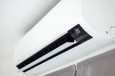 Beyaz duvar odasının arka planında klima var.