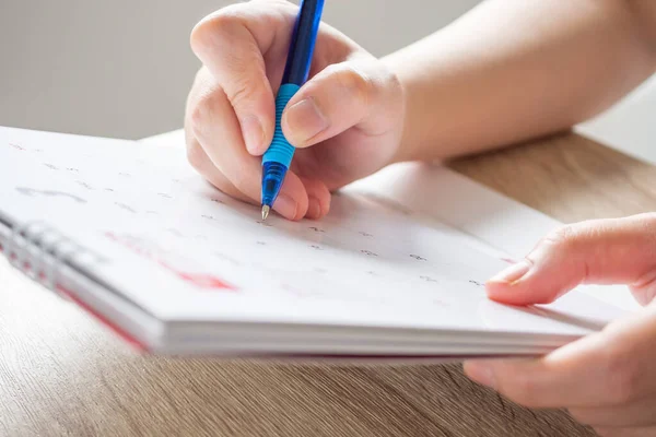 Woman hand with pen writing on calendar date business planning appointment meeting concept