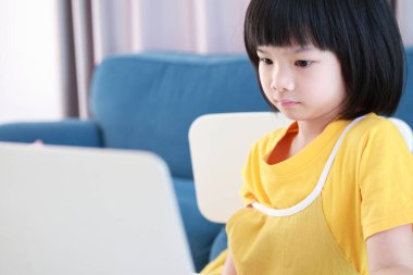 Küçük Asyalı kız öğrenci çevrimiçi evde dizüstü bilgisayar kullanıyor.