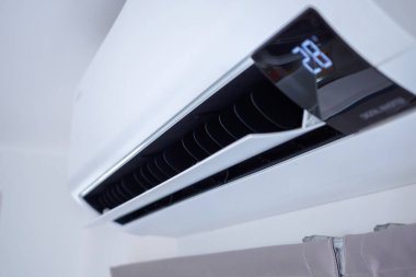 Beyaz duvar odasının arka planında klima var.