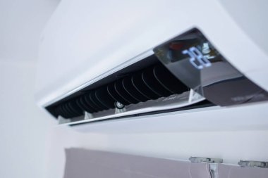 Beyaz duvar odasının arka planında klima var.