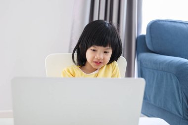 Küçük Asyalı kız öğrenci çevrimiçi evde dizüstü bilgisayar kullanıyor.