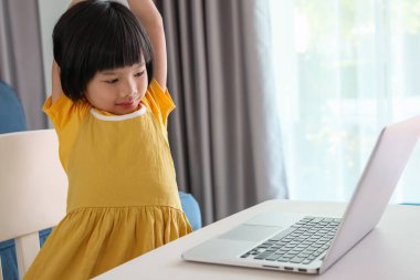 Küçük Asyalı kız öğrenci çevrimiçi evde dizüstü bilgisayar kullanıyor.