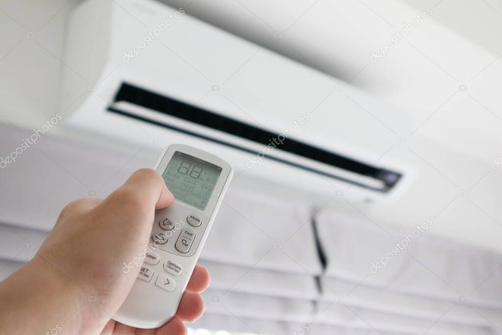 Hand with remote control directed on air conditioner