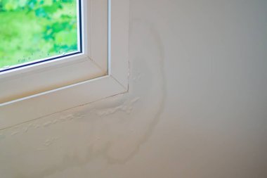 Pencerenin yanındaki duvarda su lekesi var, boya soyuluyor.