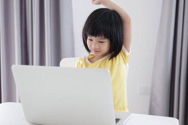 Küçük Asyalı kız öğrenci çevrimiçi evde dizüstü bilgisayar kullanıyor.