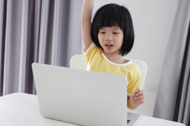 Küçük Asyalı kız öğrenci çevrimiçi evde dizüstü bilgisayar kullanıyor.