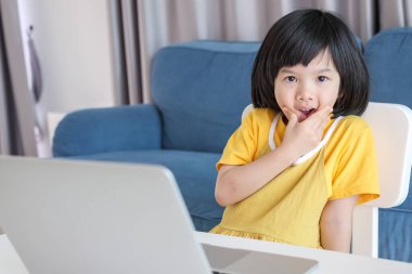 Küçük Asyalı kız öğrenci çevrimiçi evde dizüstü bilgisayar kullanıyor.