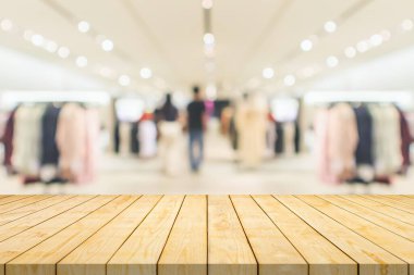 Boş ahşap masa üstü ve bulanık kıyafet butiği iç alışveriş merkezinin arka planı.
