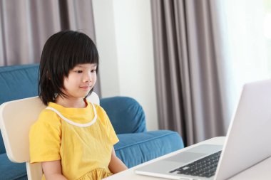 Küçük Asyalı kız öğrenci çevrimiçi evde dizüstü bilgisayar kullanıyor.