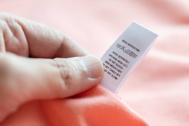 Beyaz çamaşırhanede el ele tutuşup kitap okuyoruz. Çamaşır yıkama talimatı. Pembe gömleğin üzerindeki kıyafet etiketi.