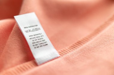 White laundry care washing instructions clothes label on pink cotton shirt