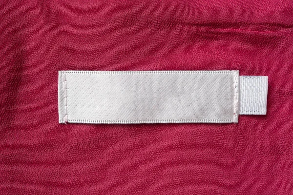 Leere Weiße Wäschepflegeetikett Auf Rotem Stoff Textur Hintergrund — Stockfoto