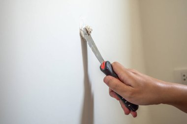 Çatlak beyaz duvarı spatulayla tamir eden adam.
