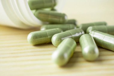 Ahşap masasında şişe bulunan bitkisel ilaç kapsülleri.