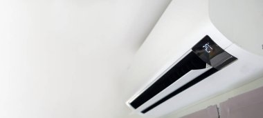 Beyaz duvar odasının arka planında klima var.