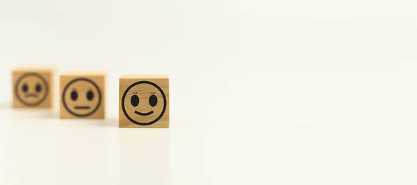 This Feedback with smile face wood cube happy smiley face icon to give satisfaction in service. rating very impressed. Black, Customer service and Satisfaction concept. Copy space, Selective focus.